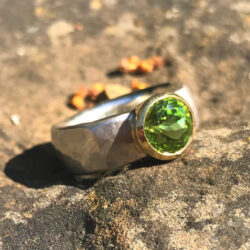 Faceted green peridot set in yellow gold on hammered silver band