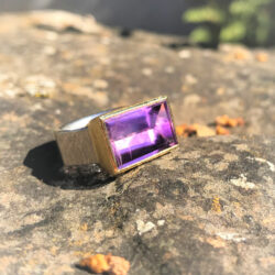 Amethyst is gold setting on wide hexagonal silver band