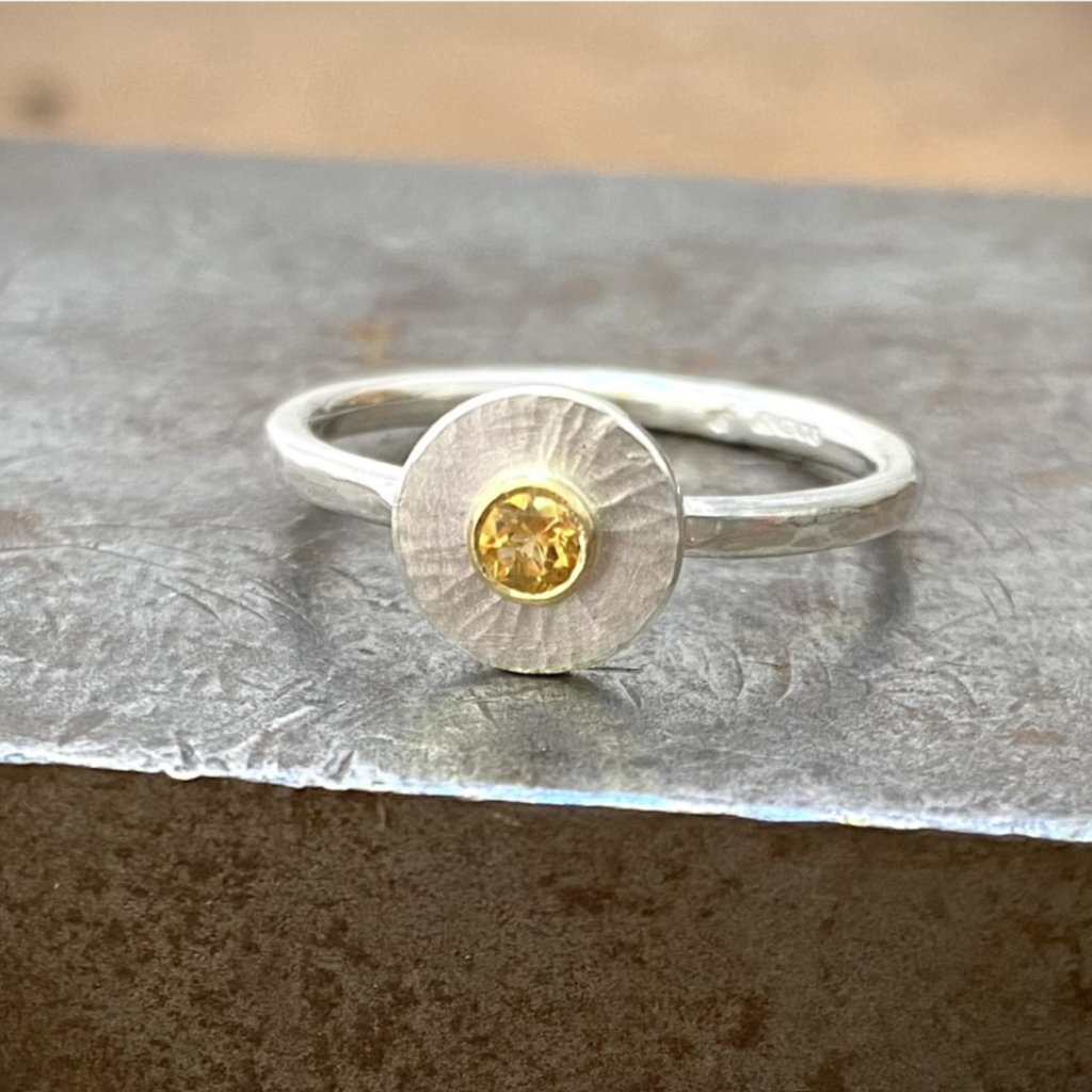 citrine in gold on round silver disk on silver band