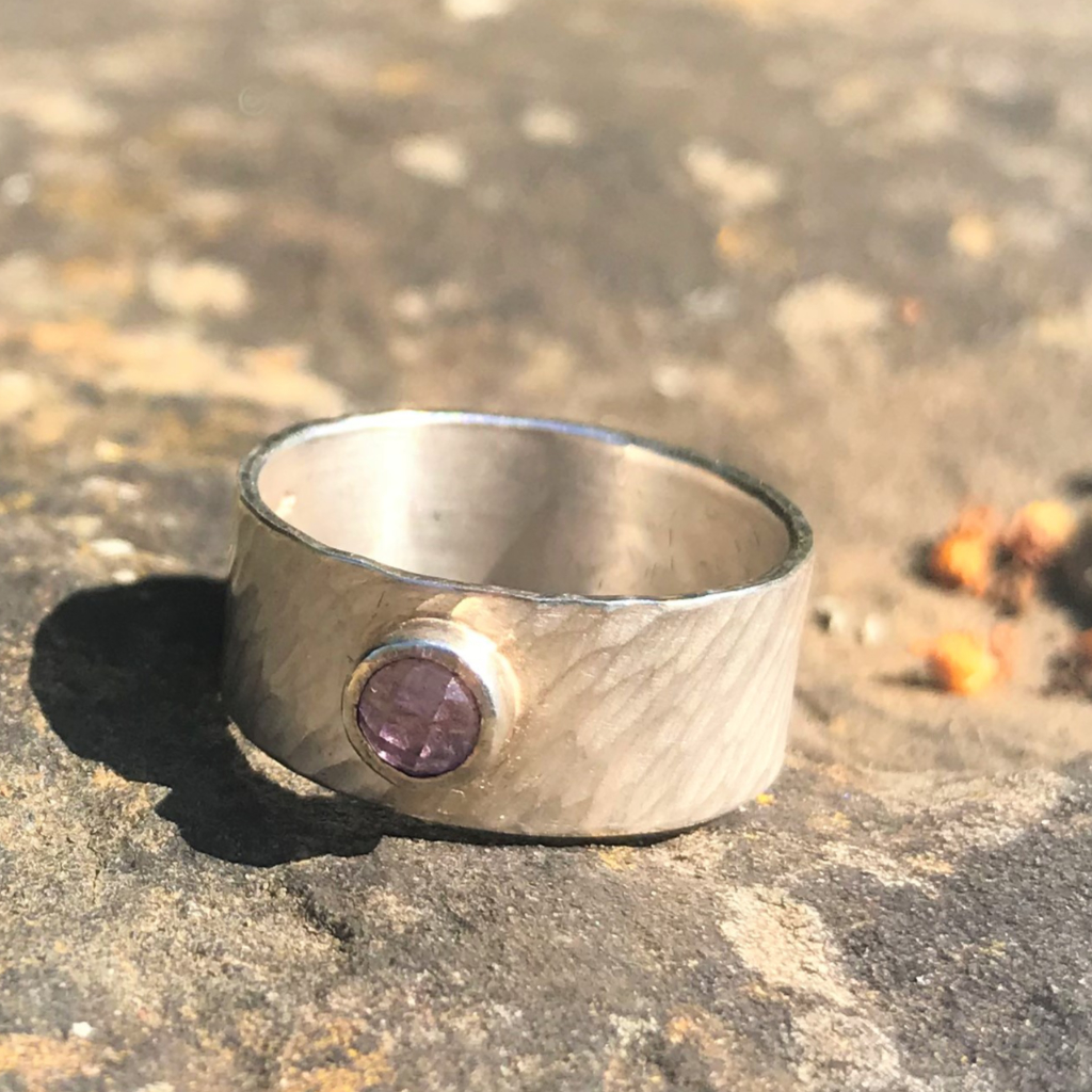 Amethyst in silver setting on wide silver rays band