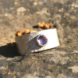 Amethyst in silver setting on wide silver rays band