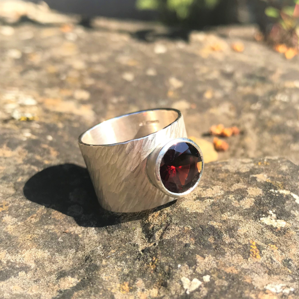 Large red garnet set in silver on wide rays silver band