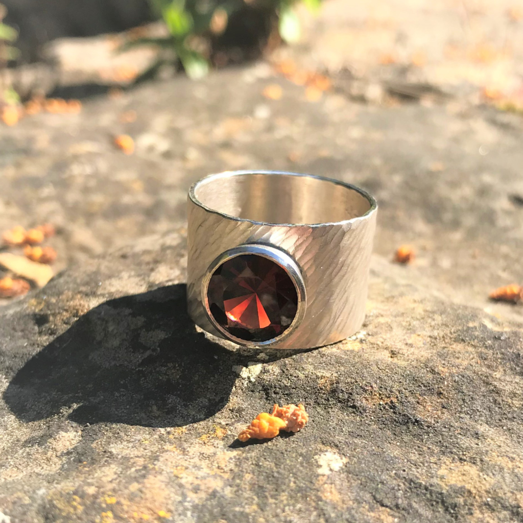 Large red garnet set in silver on wide rays silver band
