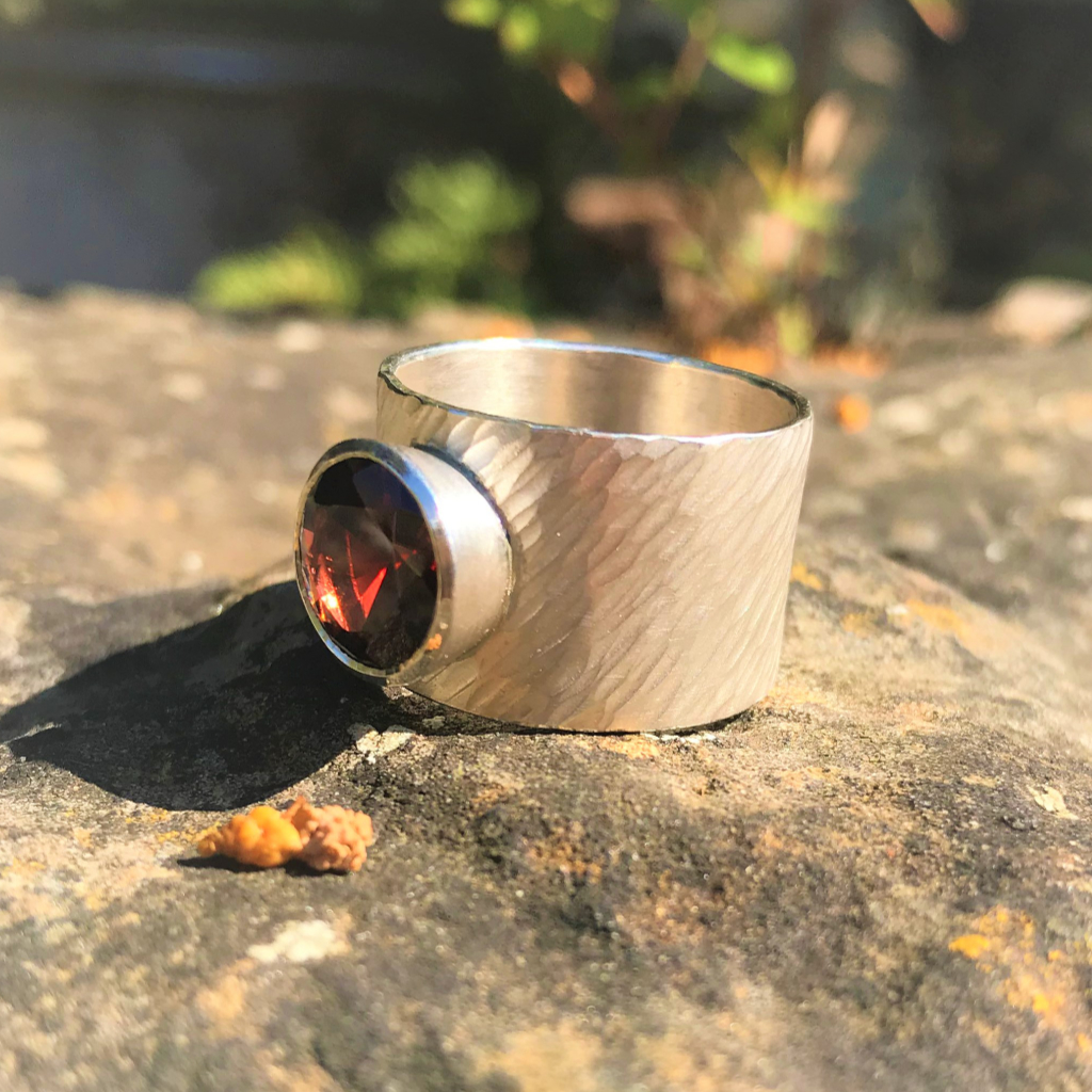 Large red garnet set in silver on wide rays silver band