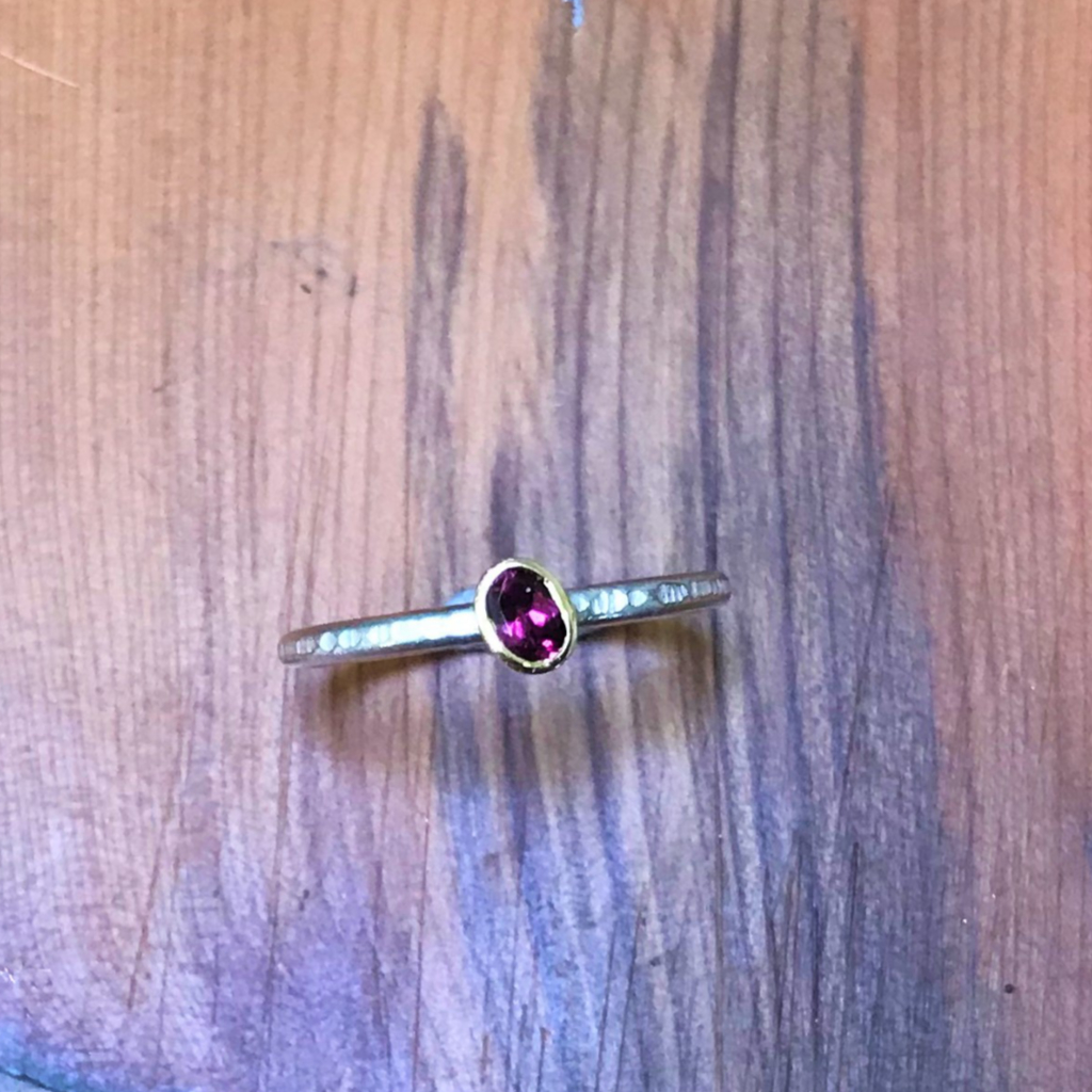 Oval purple garnet in gold setting on stacking silver band