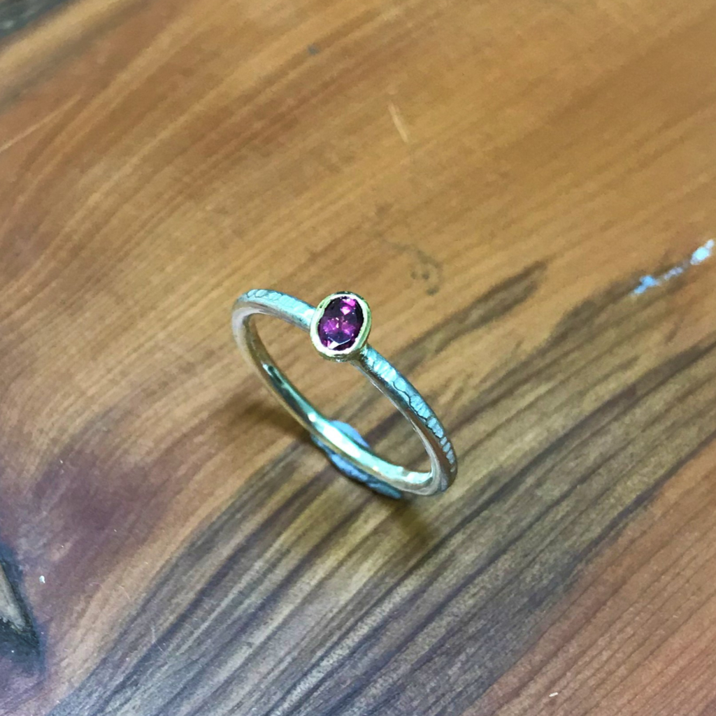 Oval purple garnet in gold setting on stacking silver band
