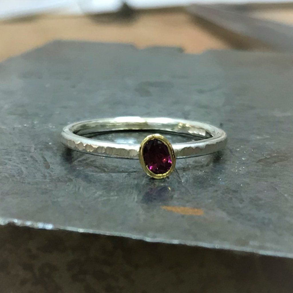 Oval purple garnet in gold setting on stacking silver band