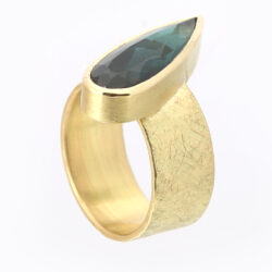 Blue/green tourmaline in gold setting on wide rays gold band